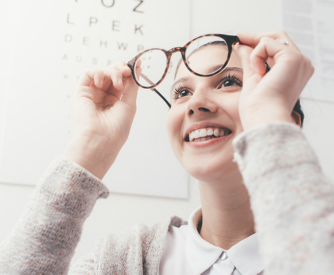Happy young woman looking into glasses